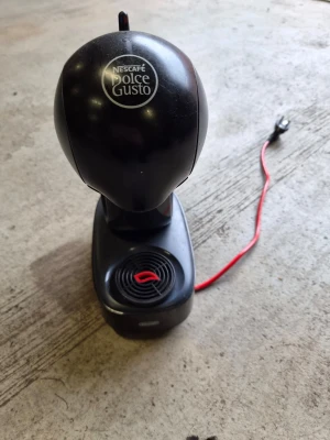 Nescafé Dolce Gusto kaffemaskin - Säljer en svart kaffemaskin från Nescafé Dolce Gusto. Maskinen har en rundad form och en röd strömkabel. Tillverkad i plast och har en enkel spak för att välja mellan varmt och kallt vatten. Perfekt för kapselkaffe och enkel att använda.
