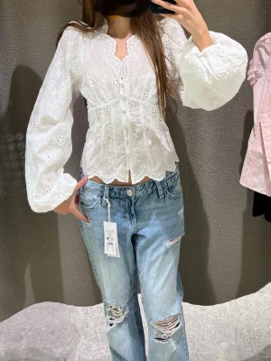 Vit broderad blus med puffärm gina tricot - Söt vit blus med broderade blommor och knappar framtill. Blusen har långa puffärmar och vågig kant nertill. Från gina tricot. Oanvänd lapo kvar.