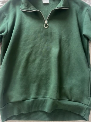 Bershka mörk grön tröja storlek M  - Det här är en mörkgrön tröja med en dragkedja. Tröjan kommer dessutom också med fickor på sidan som gör den ännu mer praktiskt. Perfekt för vintern/höst. Nypriset tror jag log på 450kr.