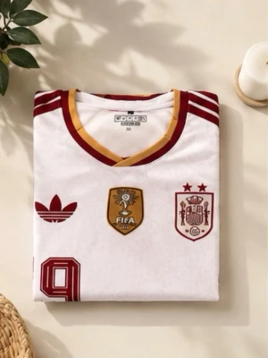 Vit Spanien matchtröja  - Vit Spanien matchtröja från Adidas med röda och guldiga detaljer. Tröjan har nummer 19, FIFA-märke och Spaniens landslagsemblem på bröstet. Klassiska Adidas-ränder på axlarna och V-ringad krage med gul och röd kant. Tillverkad i lätt och ventilerande material.