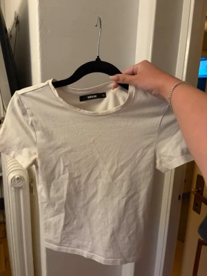 Vit basic t-shirt från Bik Bok - En enkel vit t-shirt från Bik Bok i storlek XS. Modellen har rund halsringning och korta ärmar. . Perfekt att matcha med jeans eller kjol för en clean och stilren look.