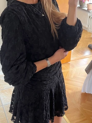 Gina klänning - Säljer en svart kort klänning med blommigt mönster och långärmade puffärmar från Gina. Använd 1 gång💞