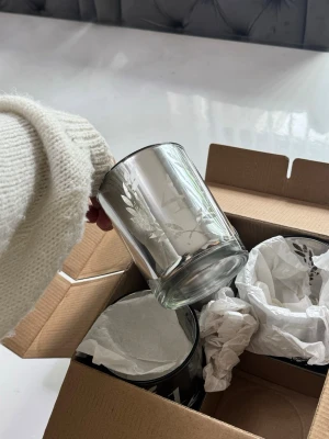 Silvriga advent ljuslyktor med siffror - Fyra silvriga ljuslyktor i glas med ingraverade siffror och dekorativa bladmotiv. Perfekta för att skapa mysig stämning hemma, till exempel som adventsljusstake. Kommer i originalkartong med skyddande papper.