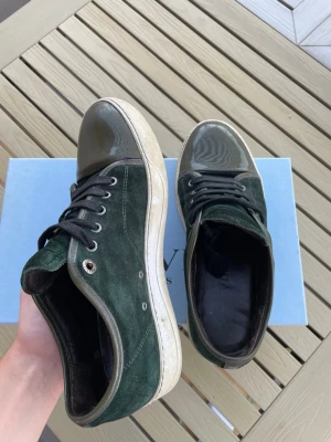 Lanvin cap toe - Feta Lanvins i mörkgrön mocka med detaljer i grönt lack på tån och hälen. Skorna har svarta skosnören och vit sula. Varsamt använda i min ägo, säljes pga för små. Stl 40-41 