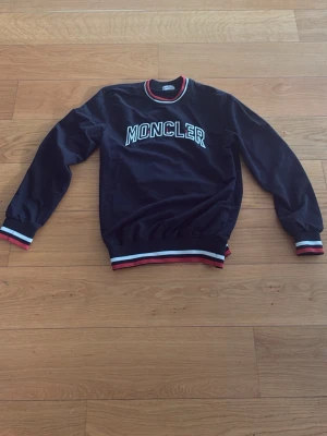 Svart Moncler Sweatshirt - Tjena 👋 Nu säljer jag min sjukt snygga svarat sweatshirt från Moncler med vit logga på bröstet. Tröjan har ribbade muddar och nederkant med röd och vit rand. Rund halsringning med samma randiga detalj. Perfekt för en stilren och sportig look. Hör av dig vid minsta fundering eller fråga! 👇