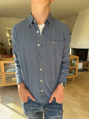 Hollister randig skjorta blå herr overshirt vintage - Klassisk fint randig skjorta från Hollister i mörkblått och vitt. Stilren modell med button down-krage och den välkända loggan broderad på bröstet. Ett perfekt basplagg till garderoben som enkelt kan kläs upp eller ner. Mycket fint och välvårdat skick.#hollister #randigskjorta #stripes #classic #preppystyle #skjorta #herrskjorta #basplagg #casual #mode