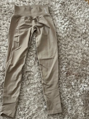 Beige impact tights från DFINE med låg midja - Snygga beige tights från DFINE i färgen ”feather beige” med  låg midja. Tillverkade i stretchigt material som passar perfekt för träning eller gym. Tight passform och scrunch-detalj bak för extra form. 