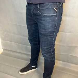 Replay Anbass jeans mörkblå W33/32 - Replay anbass jeans i storlek W33/L32. Mörkblå denim med skön passform och lite stretch som gör dem bekväma. Bra skick utan hål eller fläckar, bara lite slitningar. Nypris runt 1500–2000 kr.  Mått:A:46cm, B: 29 cm, C: 16cm, D: 80 cm. 