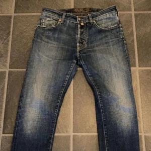 Blå jeans från Jacob Cohen, storlek 32 - Snygga blå jeans från Jacob Cohen i klassisk tvätt med slitna detaljer och kontrastsömmar. Modellen har fem fickor, logopatch bak och råa kanter vid myntfickan. Jeansen är tillverkade i bomull och har en rak passform. Pris kan diskuteras 
