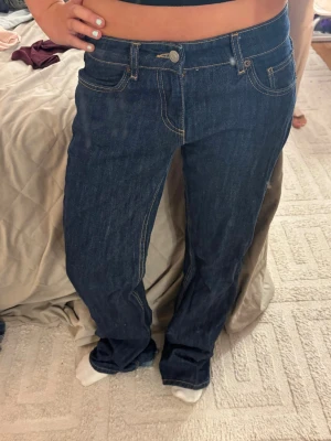Mörkblå  wide jeans med kontrastsömmar - Säljer ett par mörkblå jeans med  wida ben och snygga kontrastsömmar. Klassisk femficksmodell med normal midja och knappgylf. Jeansen har en tidlös look och passar perfekt till många olika stilar. Materialet är kraftig denim i bomull. Dessa  och är helt slutsålda. och dessa är knappt använda 
