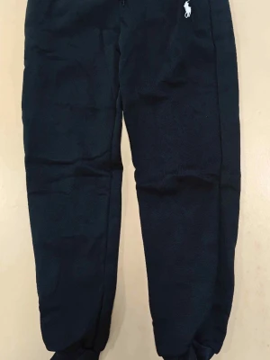 Svarta mjukisbyxor Ralph lauren  - Svarta mjukisbyxor med resår i benslut och midja samt dragsko. Byxorna har sidofickor och en liten vit logga broderad framtill. Tillverkade i mjukt och bekvämt material, perfekta för chill dagar eller träning.