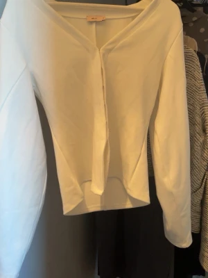 Vit cardigan från Nelly - Säljer en stilren vit cardigan från Nelly i storlek M. Koftan har v-ringning, långa ärmar och knäppning framtill. Perfekt att slänga över en topp för en clean look. Materialet känns mjukt och bekvämt mot huden.