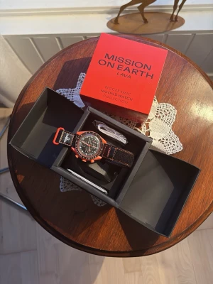 Omega x Swatch MoonSwatch Lava klocka - Säljer en Omega x Swatch MoonSwatch Lava från Bioceramic MoonSwatch Collection. Klockan har en svart urtavla med vita och orange detaljer, orange boett och svart textilband med orange sömmar. Kommer i originalförpackning med tillbehör.