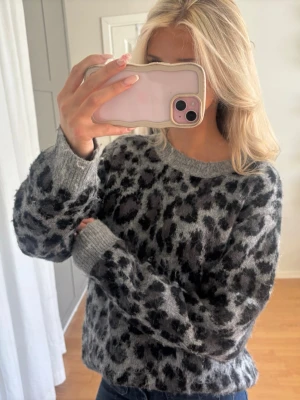 Grå leopardmönstrad stickad tröja - Mysig stickad tröja i grått med svart leopardmönster. Tröjan har rund halsringning, långa ärmar och ribbade muddar vid ärmslut och nederkant. Använd 1 gång, så mysig💗