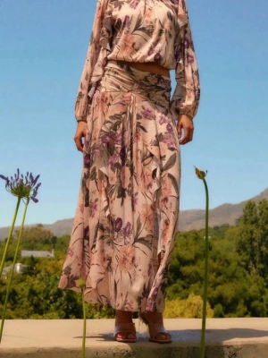 Lång kjol  från NEXT - Säljer en lång, flowy kjol med blommigt mönster i rosa, lila och gröna nyanser. Kjolen har en omlott-look och faller snyggt längs benen. Perfekt för dig som gillar romantiska och bohemiska vibes.