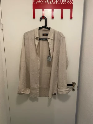 Morris skjorta - Riktigt snygg beige skjorta från Morris med krage och knäppning framtill. Helt oanvänd då skjortan sitter lite för stort på mig. Köpt för 900 men mitt pris är 499! Pris kan diskuteras 