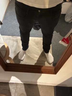 Svarta replay jeans - Säljer ett par svarta slim fit jeans med klassisk femficksdesign och normalhög midja. Jeansen har smal passform och är tillverkade i ett stretchigt material som sitter snyggt på benen. Perfekta för dig som gillar en stilren och enkel look.