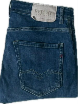 Blå jeans från Replay - Snygga blå jeans från Replay med klassisk femficksdesign och tydliga sömmar. Jeansen har en mörk tvätt och detaljerade bakfickor med V-formad söm. Tillverkade i slitstarkt denimtyg som ger en tidlös look.