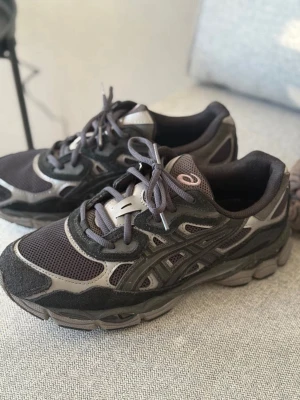 ASICS GEL NYC svarta - Säljer ett par svarta och grå sneakers från Asics med mesh- och mockadetaljer. Skorna har en chunky sula och klassisk Asics-logga på sidan. Perfekta för dig som gillar sportig och trendig stil. Kommer även med vita snören 