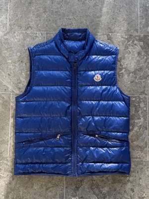 Moncler ”Gui” väst - Säljer denna snygga moncler gui väst! | Storlek 4, passar medium/large | Skick: 7/10, lite skavanker, se bilder. Inget som syns vid användning | Pris: 1300kr ‼️ sjukt bra pris! | Garanterar alltid äkthet på alla våra varor.
