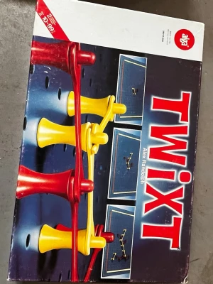 Twixt brädspel - Säljer brädspelet Twixt från Alga, ett strategispel med blå spelplan och röda samt gula spelpjäser. Spelet innehåller plastpjäser och spelbräde med hål samt instruktioner. Perfekt för dig som gillar utmanande brädspel.