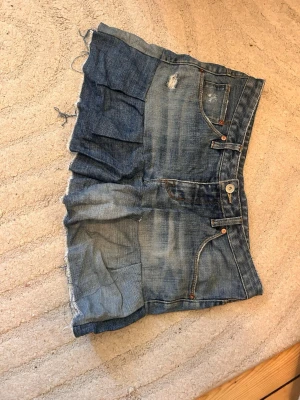 Blå lågmidjade jeansshorts med volang - Helt nya , aldrig använt , midjemått rakt över : 42  ,lågmidjade 