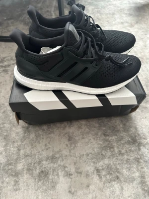Svarta sneakers med vit sula - Snygga svarta sneakers med vit sula och ventilerande mesh-ovandel. Skorna har svarta snören och detaljer i plast längs sidorna. Yttersulan har ett unikt mönster för bra grepp och komfort. Perfekta för dig som gillar stilrena och sportiga skor.