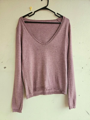 Zadig & Voltaire Stickad tröja  - Härligt mjuk tröja i kaschmir från Zadig & Voltaire i varm syrenlila ton. Fin lite rundad V-ringning. Fina detaljer med broderat mönster. Tyvärr är lappen bortklippt men man ser loggan inbroderad på sista bilden. Uppskattar storlek M ungefär. Lagad på sidan där det var ett litet hål efter lappen, ses på sista bilden hur det ser ut utifrån. 