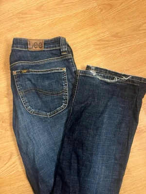 Mörkblå Lee jeans med raka ben - Snygga mörkblå jeans från Lee med klassisk femficksmodell och raka ben. Jeansen har kontrastsömmar och Lee-logga på bakfickan. Tillverkade i slitstarkt denimtyg som ger en cool och avslappnad look.
