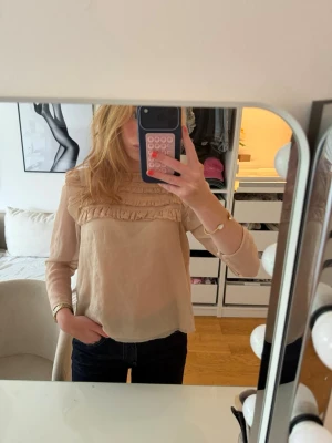 Beige blus med volangdetaljer - Söt beige blus med lång ärm och volangdetaljer från hm som ej säljs längre🫶🏻Står att den är i storlek 36 men skulle säga att den är mer i xs