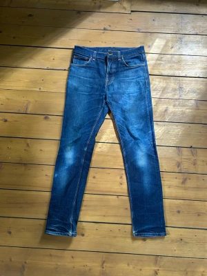 Nudie jeans steady Eddie  - Snygga blå  jeans med klassiska fades och fem fickor. Jeansen har en något tvättad look  och bakfickor med vågig detaljsöm. Tillverkade i denim med stretch för skön passform. Storlek 32/32. Tveka inte vid frågor. 