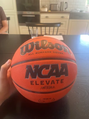 Wilson NCAA basketboll storlek 6 - Säljer en orange basketboll från Wilson, modell NCAA Elevate. Bollen har svart och grå text, klassisk struktur och är tillverkad i slitstarkt syntetmaterial för spel på alla underlag. Perfekt för dig som vill träna eller spela basket med kompisarna.