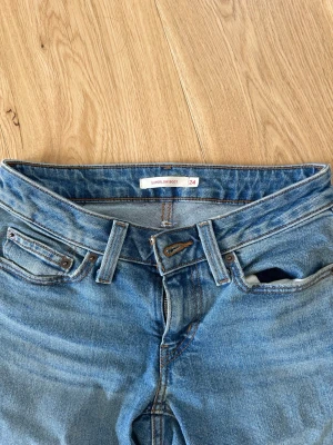 Levi's Superlow Boot jeans ljusblå - Säljer ett par ljusblå Levi's Superlow Boot jeans med klassisk femficksmodell och bootcut. Jeansen har Levi's ikoniska läderpatch bak och röda etikett på fickan. Tillverkade i denim med snygga kontrastsömmar och låg midja.