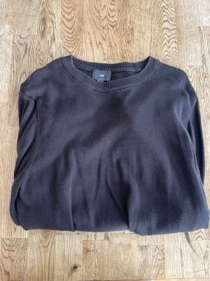 Brun stickad tröja - En enkel och stilren brun tunn stickad tröja från H&M i slim fit-modell. Tröjan har rund halsringning och ribbade muddar vid hals, ärmslut och nederkant.