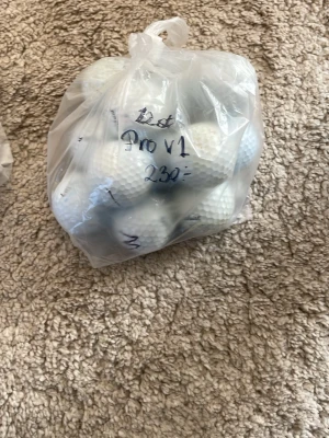  vita golfbollar prov1 och prov1x - En plastpåse fylld med vita golfbollar av modellen Pro V1 och PRO v1x. Bollarna har klassisk dimple-yta och är förpackade i en genomskinlig plastpåse med handskriven text på utsidan. Perfekt för golfentusiasten som vill fylla på sitt bollförråd.
