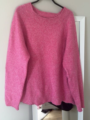 Rosa stickad tröja  - Mysig rosa stickad tröja med rund halsringning och långa ärmar. Tröjan har en avslappnad, normal passform och ribbade muddar vid ärmslut och nederkant. Perfekt för lager på lager och en färgklick i garderoben.