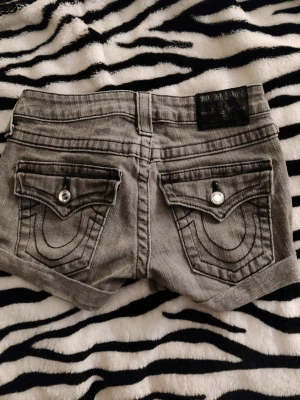 True religion shorts - Gråa true religion shorts. Min mammas från 2000 talet ganska liten i storleken.lappen är bortklippt men skulle säga att det är Xs-xxs.