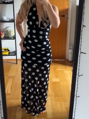 Långklänning med vita prickar - Jättevacker långklänning med vita prickar. Öppen i ryggen med en knytning i nacken samt see-trough nertill. Aldrig använd, i princip ny!