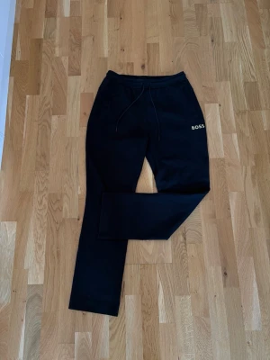 Svarta mjukisbyxor från BOSS modell HADIM strl M - Säljer ett par stilrena BOSS Hadim mjukisbyxor i svart med gulddetalj. Nypris: 1 299 kr.                                                  Storlek: M Skick: Knappt använda, toppenskick utan slitage 100% äkta. orderbekräftelse/kvitto finns kvar Lite finare mjukisbyxor i hög kvalitet när du vill vara både bekväm och snygg. Skriv vid frågor/bilder osv!