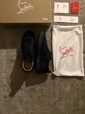 Mörkblå sneakers från Christian Louboutin - Stilrena mörkblå sneakers från Christian Louboutin med klassisk låg siluett. Och även den klassiska röda sulan undertill. Kommer med originalkartong, dustbag och äkthetskort. Anledningen till det väldigt låga priset är för att de är lite slitna😊