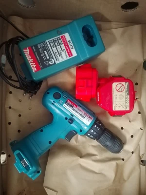 Makita borrmaskin med laddare och batteri - Makita 6313D sladdlös borrmaskin i blå plast med svart handtag, med tillhörande röd batteripack och grön batteriladdare. Perfekt för hemmafixaren som vill ha ett smidigt verktyg till olika projekt.