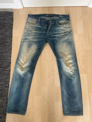 Replay jeans - Säljer ett par blå jeans med snyggt sliten tvätt och raka ben. Jeansen har klassisk femficksmodell, knappgylf och ljusa slitningar framtill och baktill för en cool, avslappnad look. Perfekta till sneakers eller boots. Modell jennon. Kolla noga på bilderna❗️❗️
