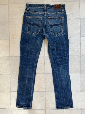 Mörkblå jeans ifrån Nudie Jeans med snygga fades - Säljer ett par sjukt feta jeans från Nudie Jeans  som är i ett mycket fint skick! —————————————————————                                                                      📐| Storlek: 31-32 (måtten finns på bild 6 & 7)                                            👖| Märke: Nudie jeans                                         🔎| Skick: Fint skick!                                               💵| Ny Pris: 1599kr                                                   ✍🏻| Skriv om du har några frågor