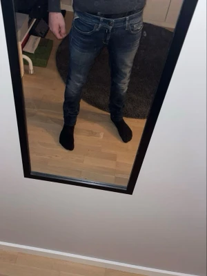 Mörkblå slim fit jeans herr - Säljer ett par mörkblå slim fit jeans med snygga slitningar och tvättade detaljer. Jeansen har klassisk femficksmodell, låg midja och smal passform. Perfekta för dig som gillar en modern och avslappnad stil. 