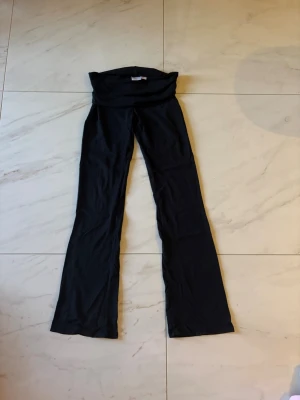 Svarta yogapants från Gina Tricot - Ett par svarta yogapants från Gina Tricot med vikt midja och utsvängda ben. 