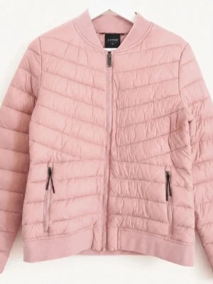 Ljusrosa pufferjacka från Everest - Snygg ljusrosa pufferjacka från Everest med quiltad design och dragkedja framtill. Jackan har två fickor med dragkedja och ribbade muddar vid ärmslut och nederkant. Perfekt för kyliga dagar och ger en trendig look. Ny utan prislapp.