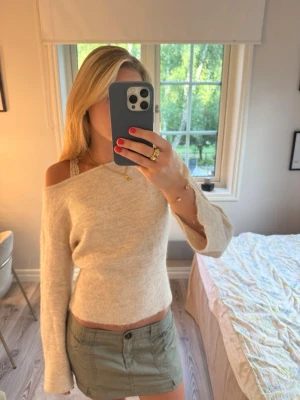 Beige stickad tröja med båtringning - Mysig beige stickad tröja med båtringning och långa ärmar. Tröjan har en mjuk, lätt figurnära passform och är tillverkad i ett tunt, skönt material.  