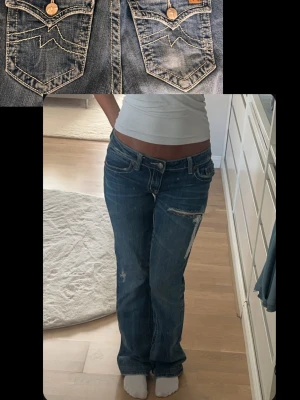 Blå bootcut jeans från Miss Me - Säljer ett par blå Miss Me jeans med slitningar och dekorativa sömmar på bakfickorna. Jeansen har låg midja, klassisk femficksmodell och detaljerade nitar. Jätte fint skick✨