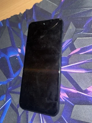 Svart Motorola Android-telefon - Säljer en svart Motorola Android-telefon med stor skärm och rundade hörn. Baksidan har trippelkamera och mattsvart finish. Perfekt för dig som vill ha en enkel och stilren mobil med bra kamera och modern design. Lagar ganska mycket det är en gammal mobil 
