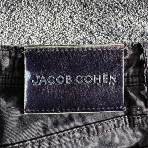 Blå byxor Jacob Cohën  - Snygga svarta byxor från Jacob Cohën, modell Nick, tillverkade i Italien. Byxorna har silverfärgade knappar med logotyp, broderade detaljer och cool text på insidan. Materialet är mjukt och lyxigt, perfekt för dig som gillar exklusiva plagg med stil. Lite skrynkliga men det är bra kvalité då jag aldrig använt för de vart för små. Kostar 3000kr nya.